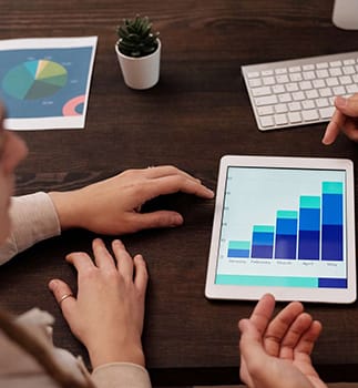 Two marketing professionals discussing business growth strategies while examining a tablet displaying a graph.